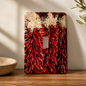 Decorative light switch cover with red chili pepper design on a wooden surface.